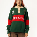 Female Model wearing a green and red, knitted rugby sweater with 'Wisdom of Age' text on a white background