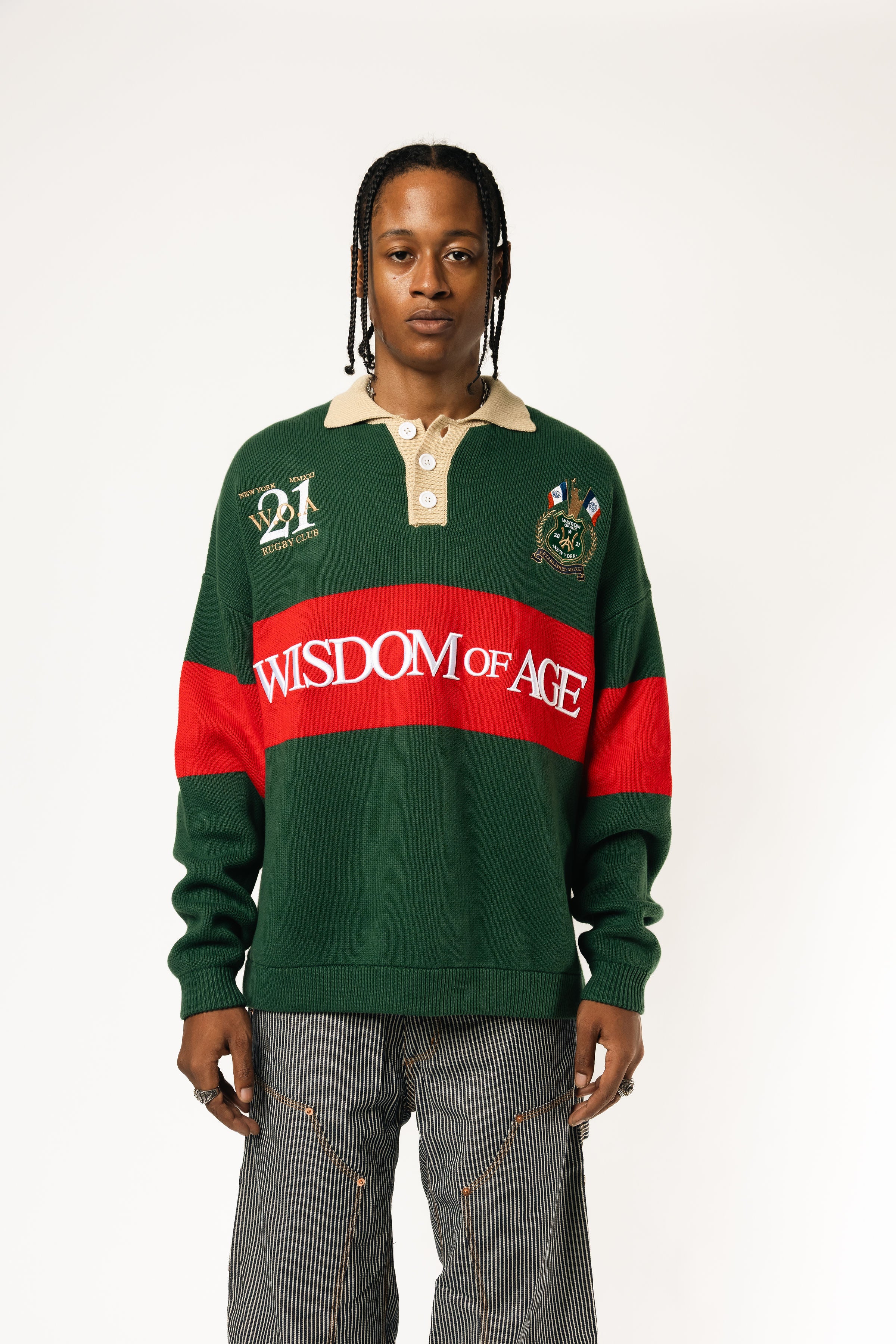Male Model wearing a green and red, knitted rugby sweater with 'Wisdom of Age' text on a white background