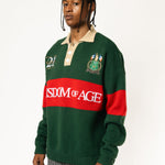 Front-side view of a Male Model wearing a green and red, knitted rugby sweater with 'Wisdom of Age' text on a white background.