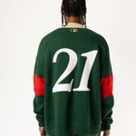 Rear view of a Male Model wearing a green and red, knitted rugby sweater with '21'  on a white background