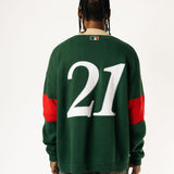 Rear view of a Male Model wearing a green and red, knitted rugby sweater with '21'  on a white background