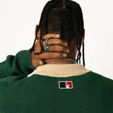 rear close up of a male Model wearing a green and red, knitted rugby sweater on a white background