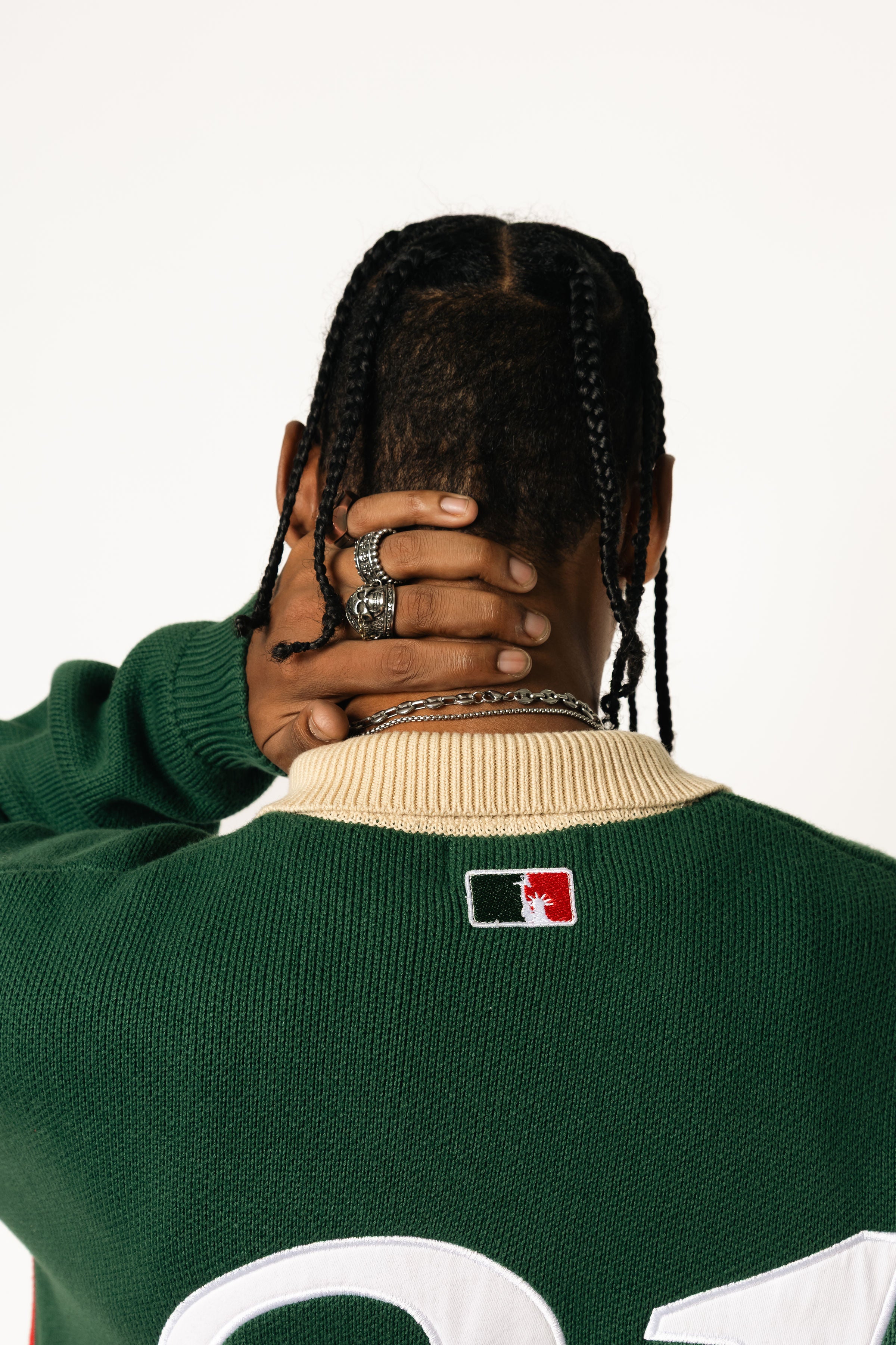 rear close up of a male Model wearing a green and red, knitted rugby sweater on a white background