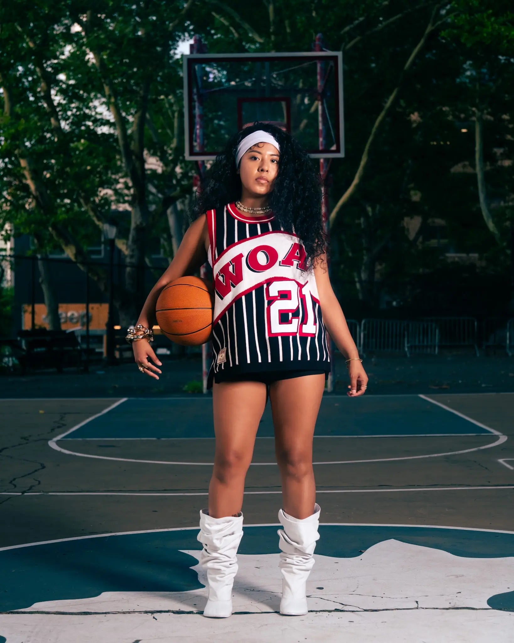 Female model wearing Wisdom Of Age Black Pinstripe Basketball Jersey while holding basketball in outdoor basketball court