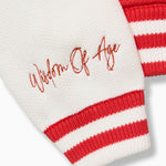 Closer look at the right sleeve with the brand name "Wisdom of Age" embroidered in a handwritten script cursive above the cuff hem.