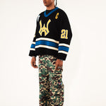 Side view Male Model wearing WOA Hockey Jersey - Static Shock with a yellow WA logo and camouflage pants on a white background