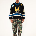 Male Model wearing WOA Hockey Jersey - Static Shock with a yellow WA logo and camouflage pants on a white background