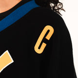 Close up on the WOA Knitted Hockey Jersey Static Shock with gold letter 'C' on a white background