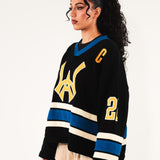 Female model Wearing The Knitted Wisdom Of Age Hockey Jersey - Static Shock with yellow and blue details on a white background