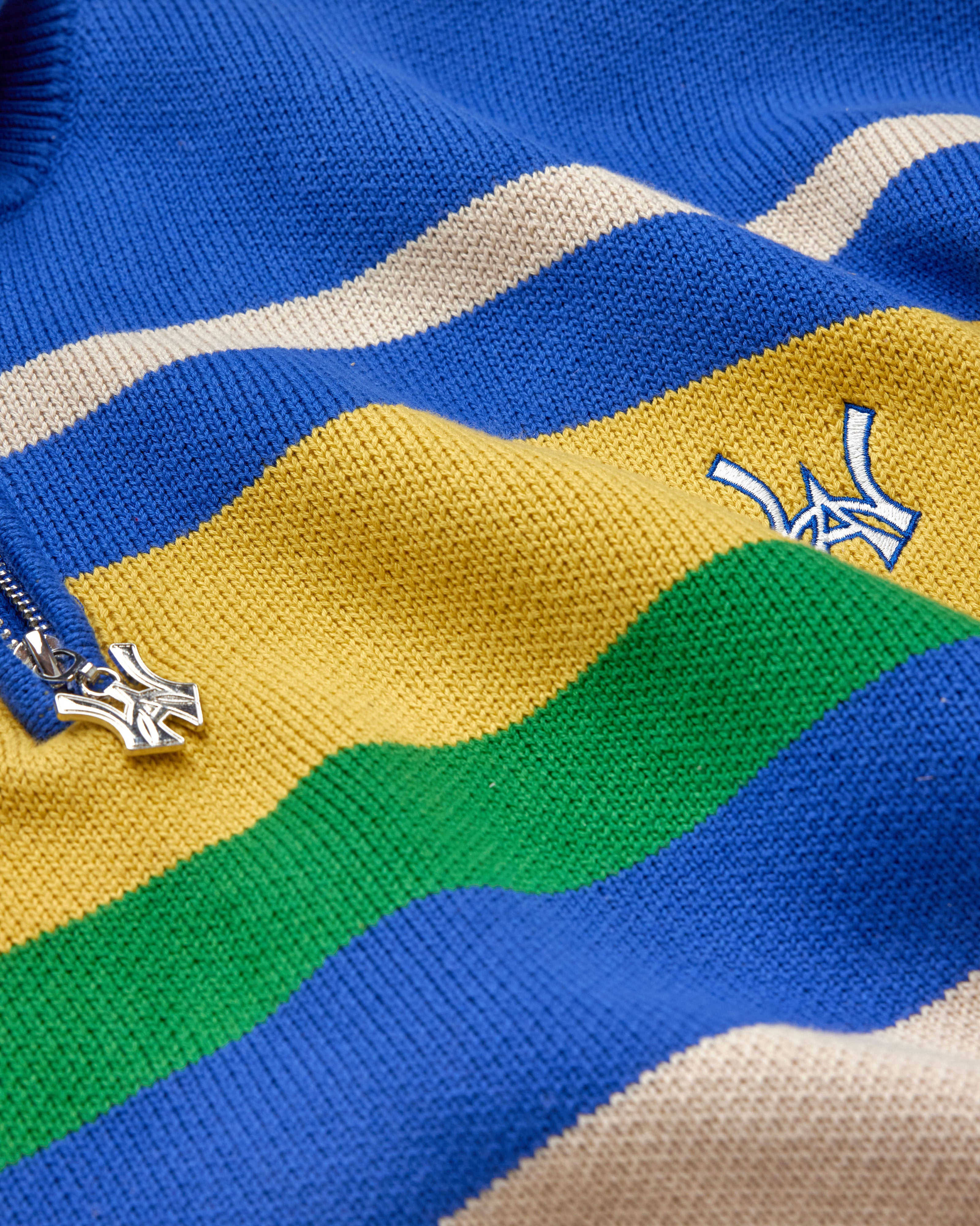 Close-up of a colorful striped sweater with the WA logo on a blue background
