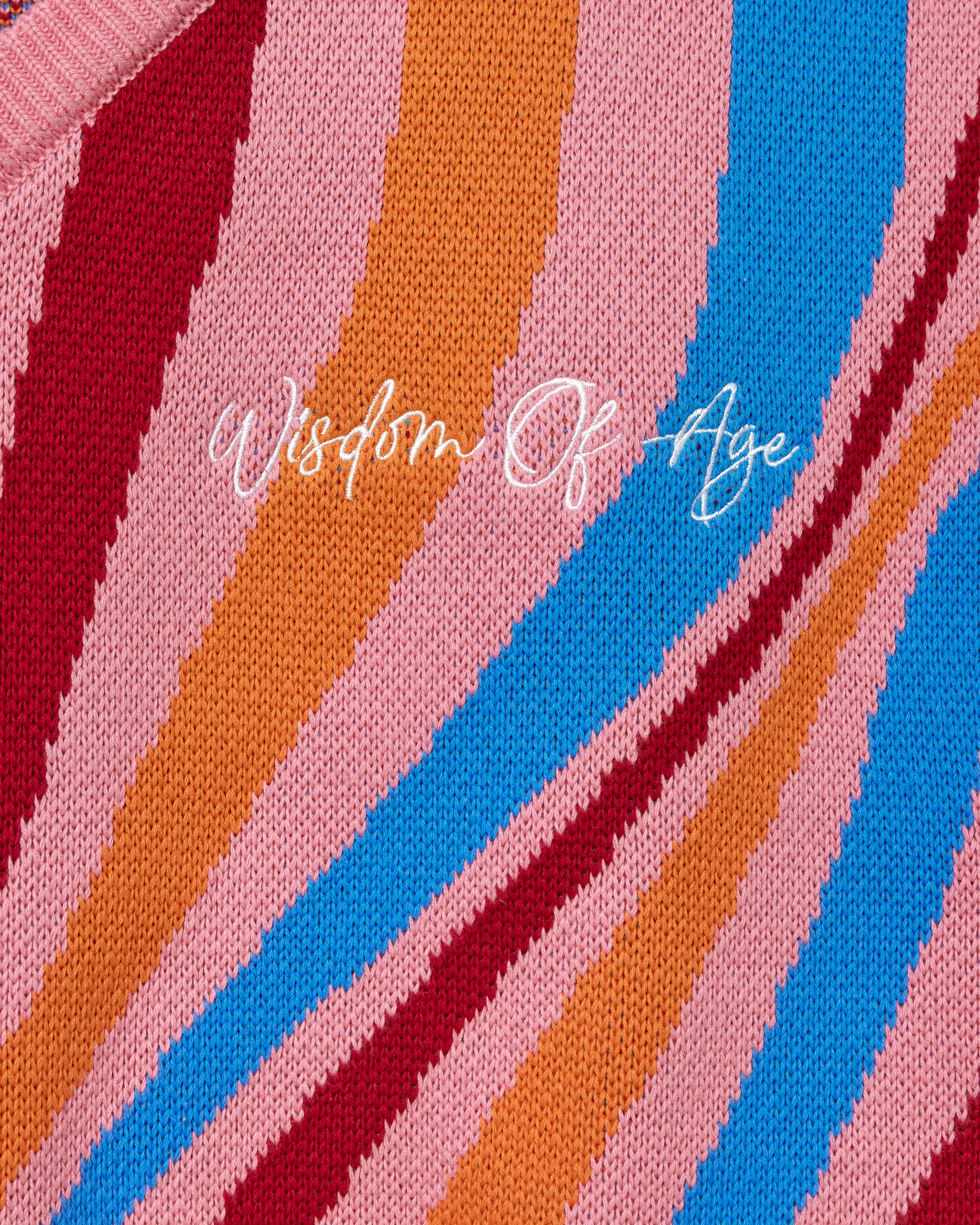 'Wisdom Of Age' embroidered on a fabric with multicolored stripes.