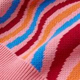 Close-up of a knitted fabric with colorful wavy pattern on pink background