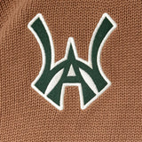 Close-up of a green WA logo with white outline on a brown textured background