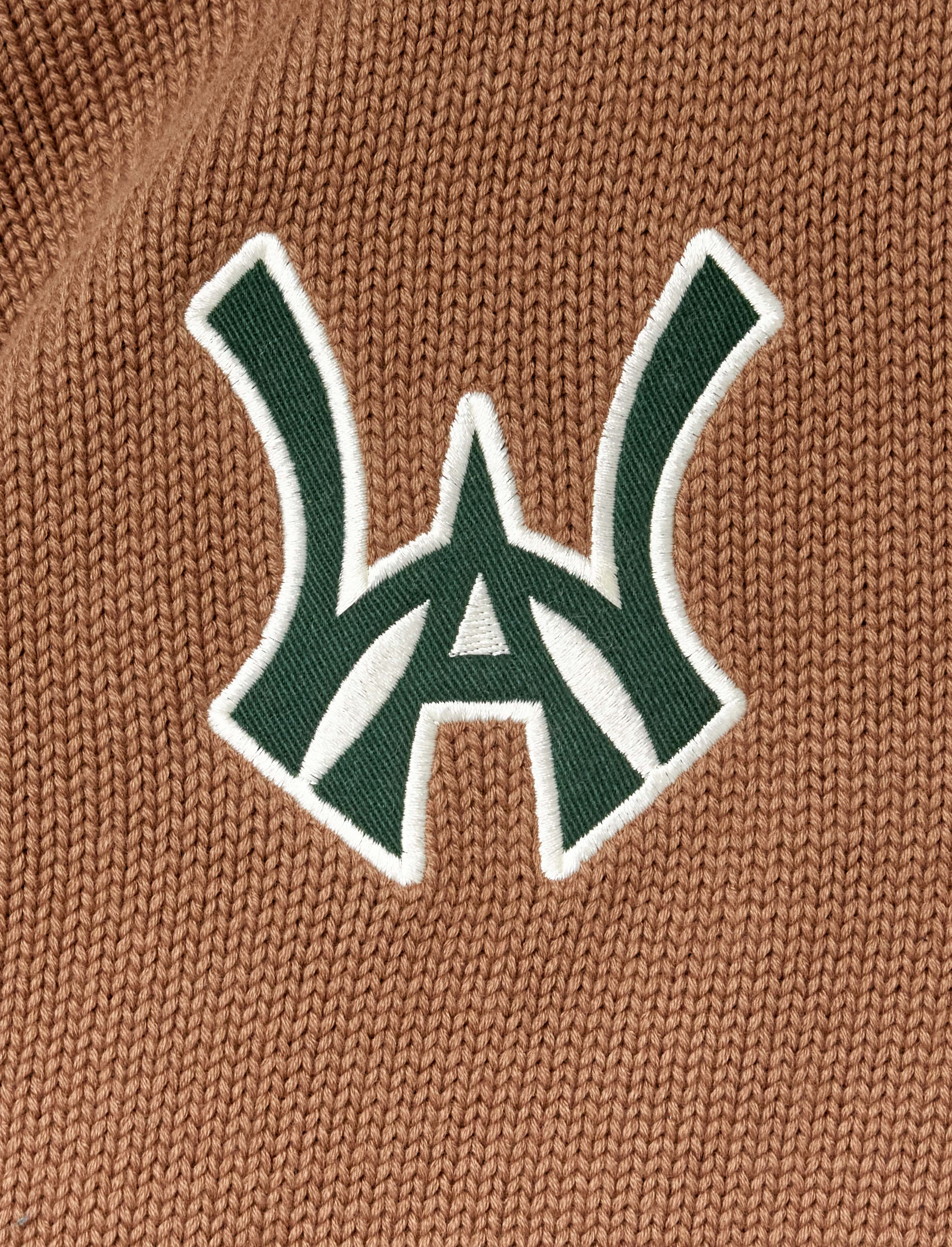 Close-up of a green WA logo with white outline on a brown textured background