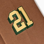 Close-up of a brown fabric with a green and gold number '21' embroidered on it.
