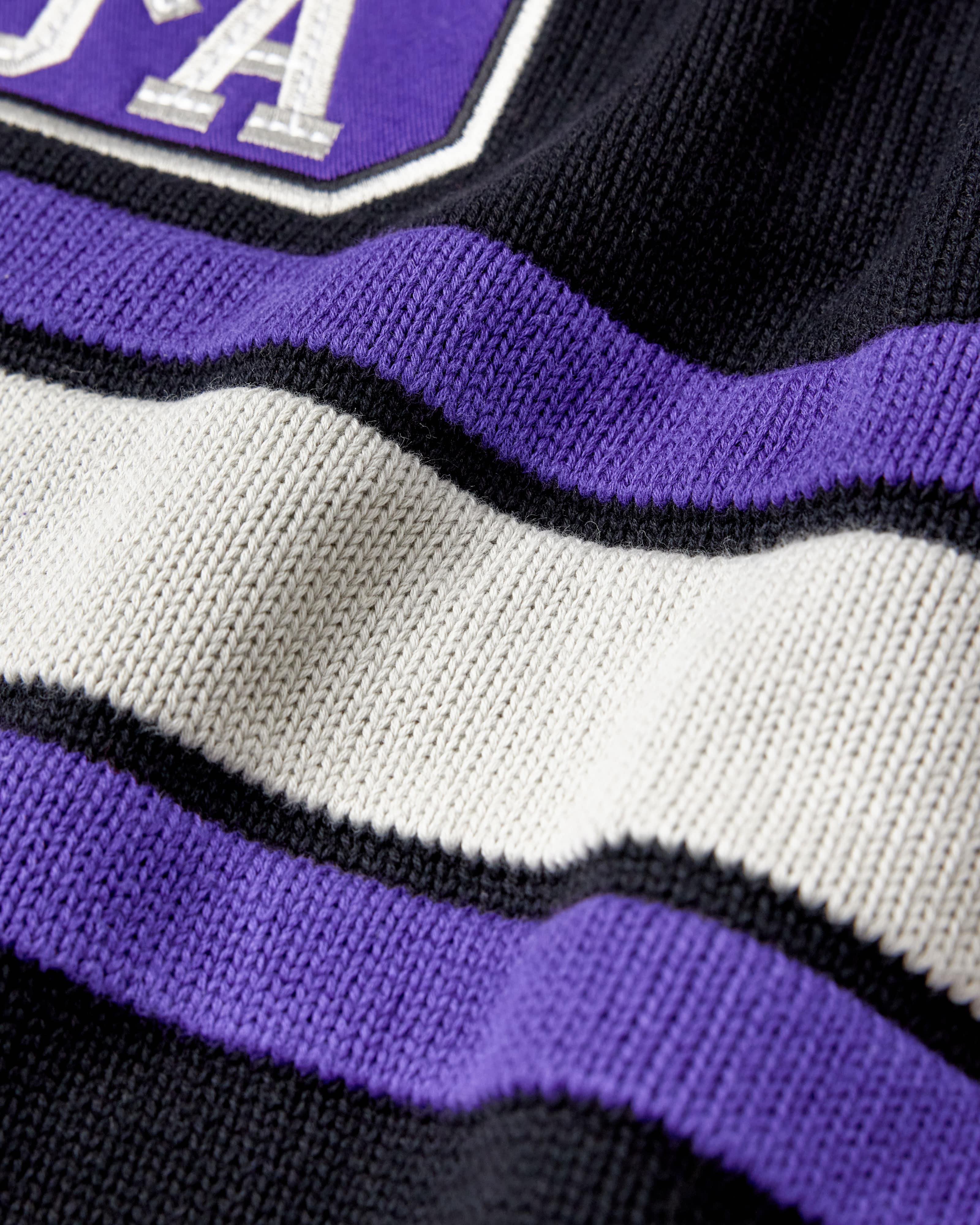 Close-up of a sweater with purple, white, and black stripes