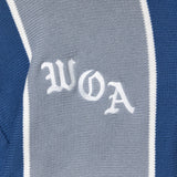 Close-up of a knitted soccer jersey with 'WOA' embroidery on a blue and gray background