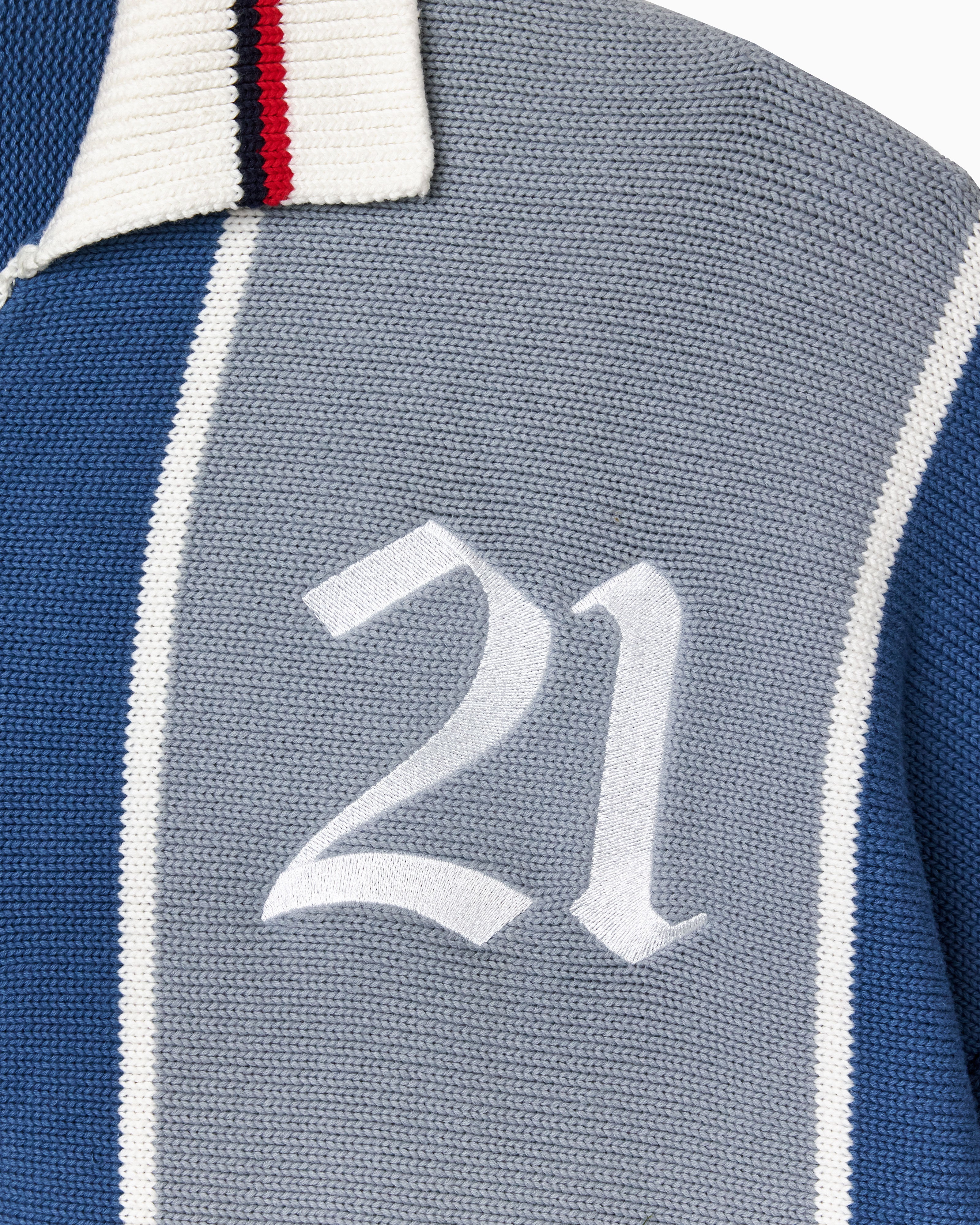 Close-up of a knitted soccer jersey with the number 21 on a blue and gray background