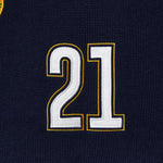 Wisdom Of Age Knit Soccer Jersey RIo. Close-up of a black knitted soccer jersey with the number 21 embroidered in white and gold.