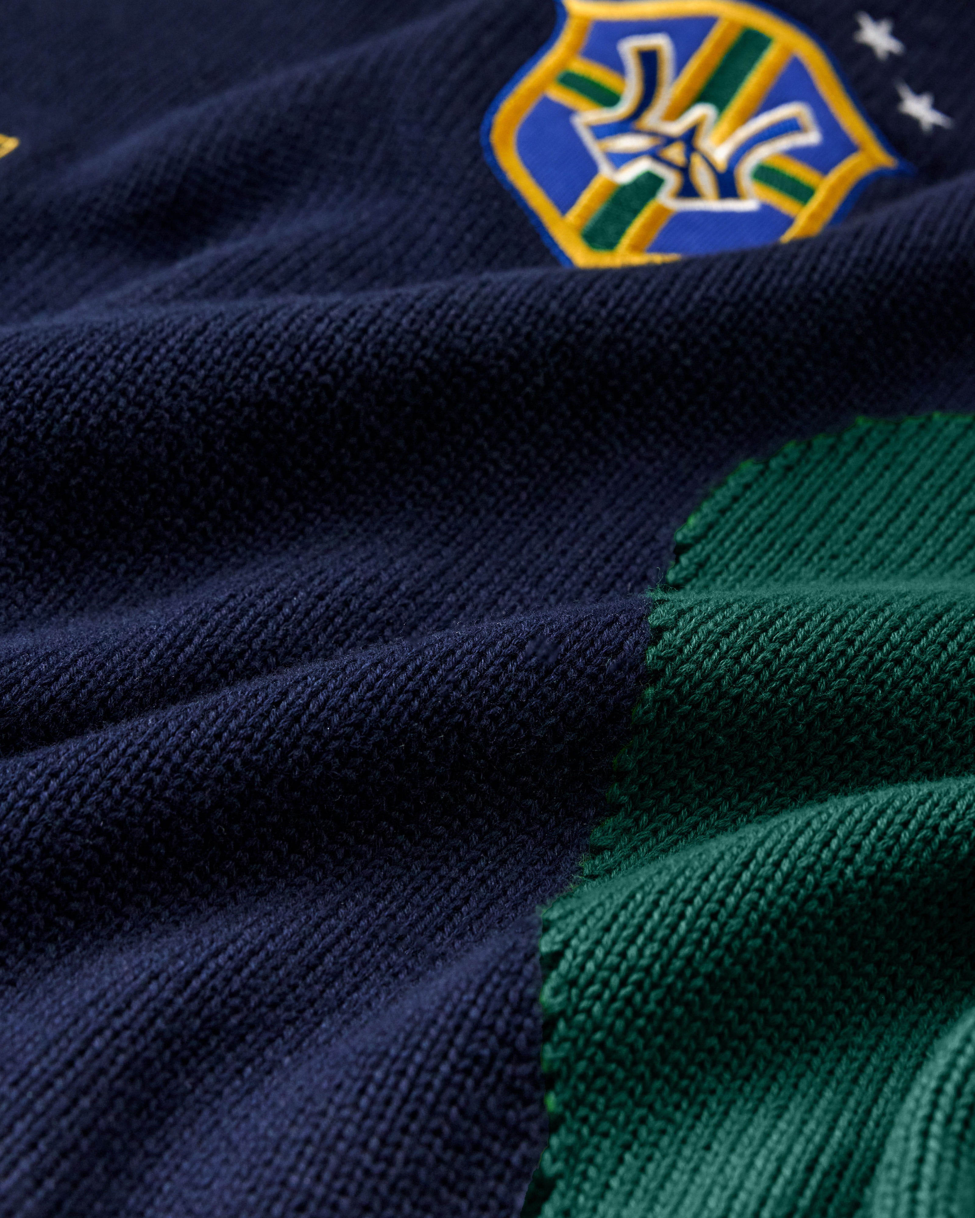 Close-up of a navy and green Wisdom Of Age Knit Soccer Jersey Rio with a WA logo in the top right corner.