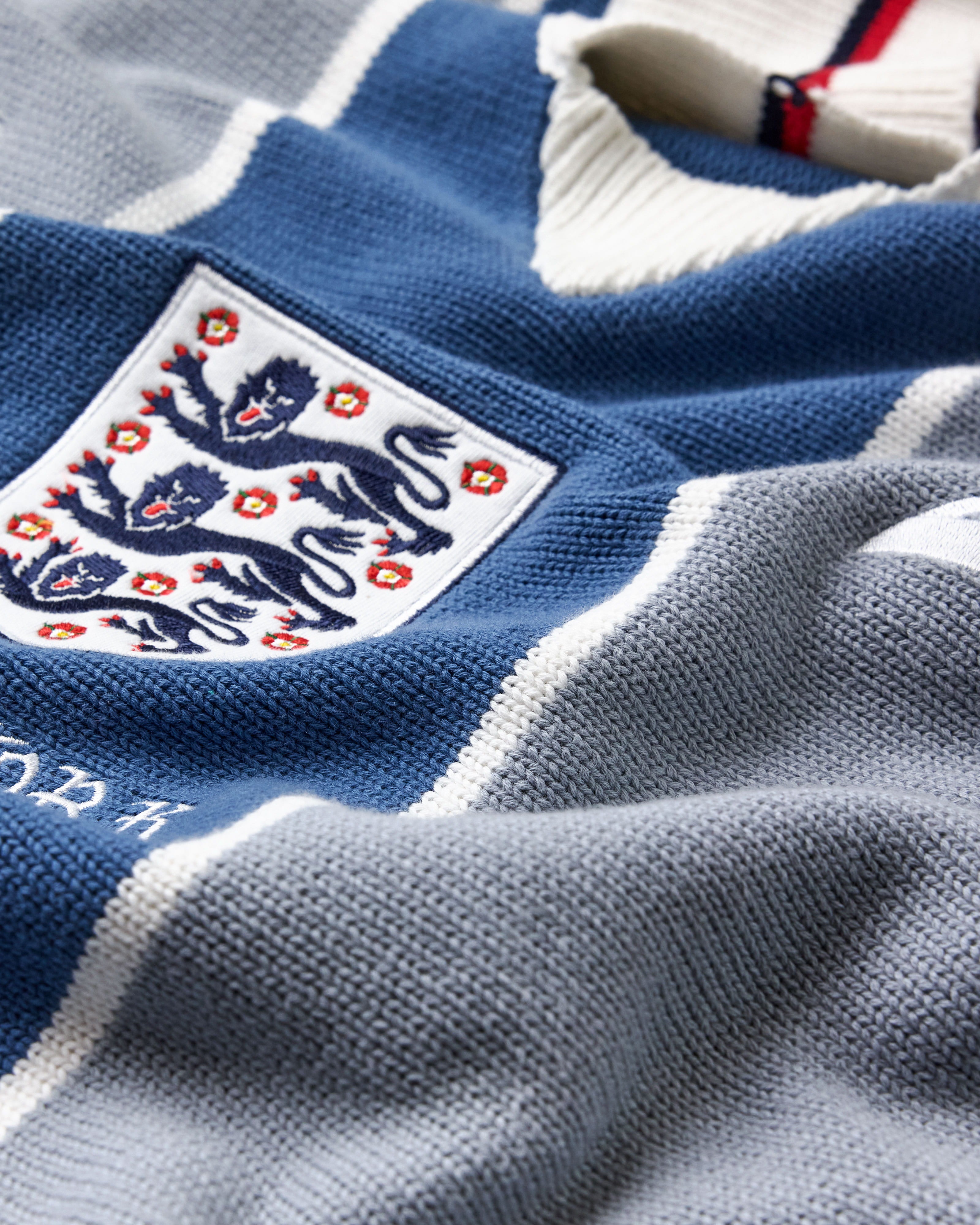 Close-up of a blue and gray sports Wisdom Of Age Knit Soccer jersey Grey Stripe with a prominent emblem.
