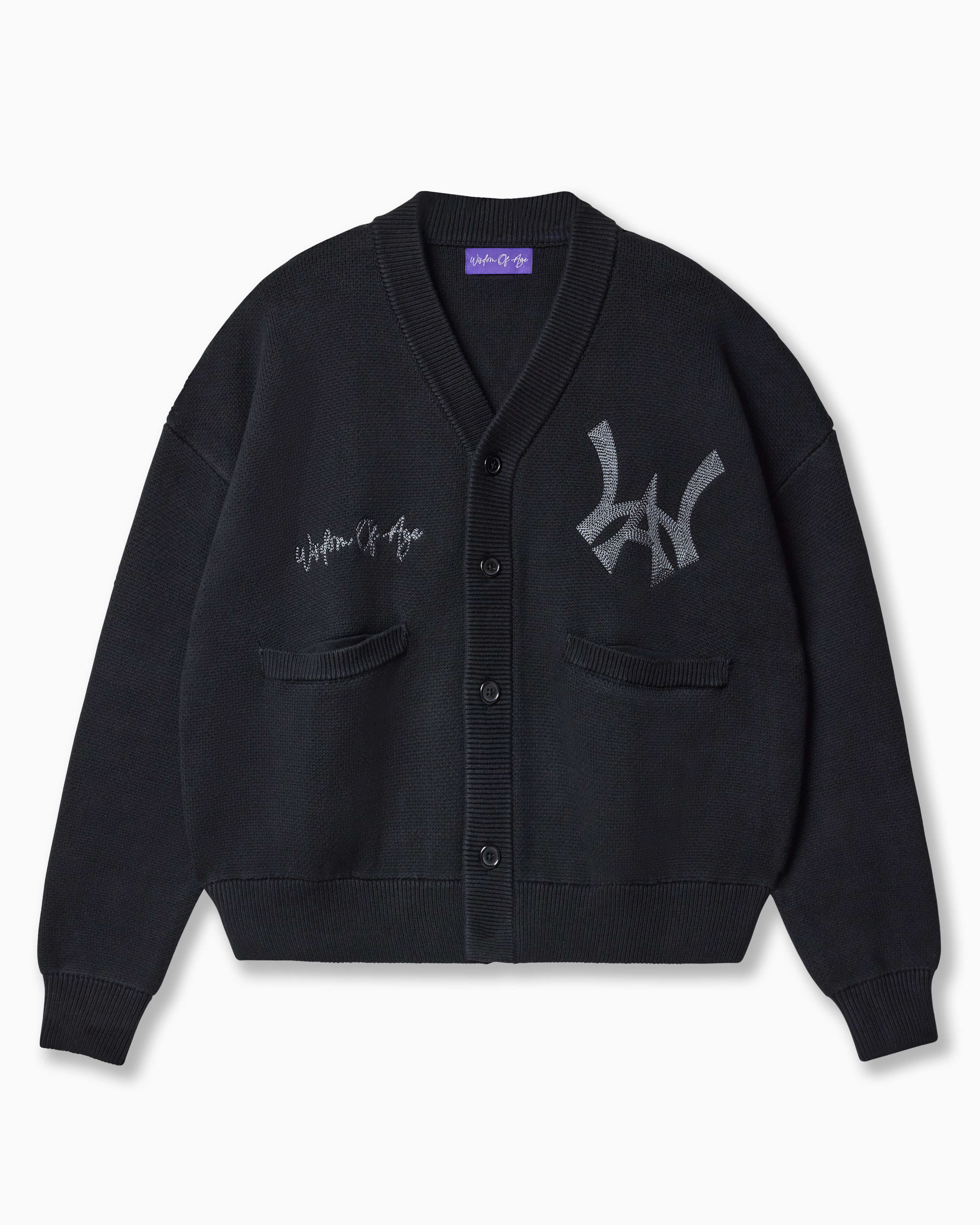 Wisdom of Age Black City Cardigan, Black Cat color wave with the WOA symbol on the top left side of the chest and the brand name “Wisdom of Age” written in script cursive on the upper right side. Two drop-in slip pockets on both sides and a 4 button placket with a v-neck drop.