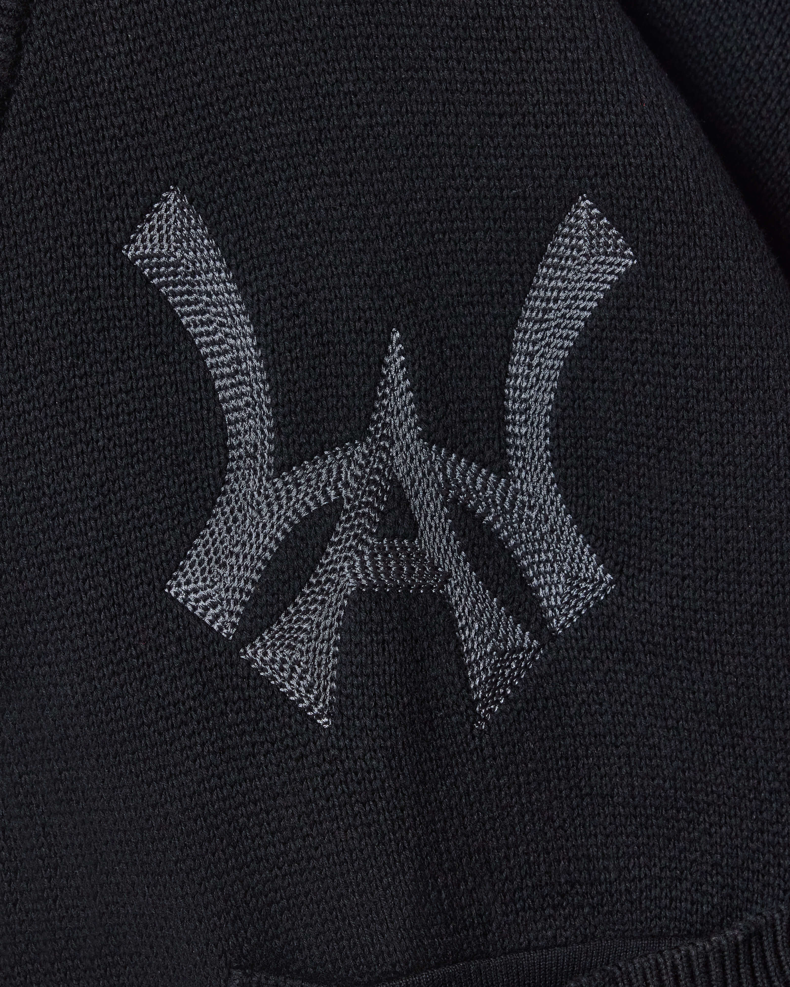 Closer look at the brand logo in a monogram font of connecting the "W" and "A" located on the upper left chest of the cardigan.