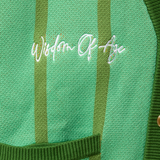 Closer Look at top right chest of the front of the cardigan with the brand name "Wisdom of Age" embroidered in a handwritten script cursive.