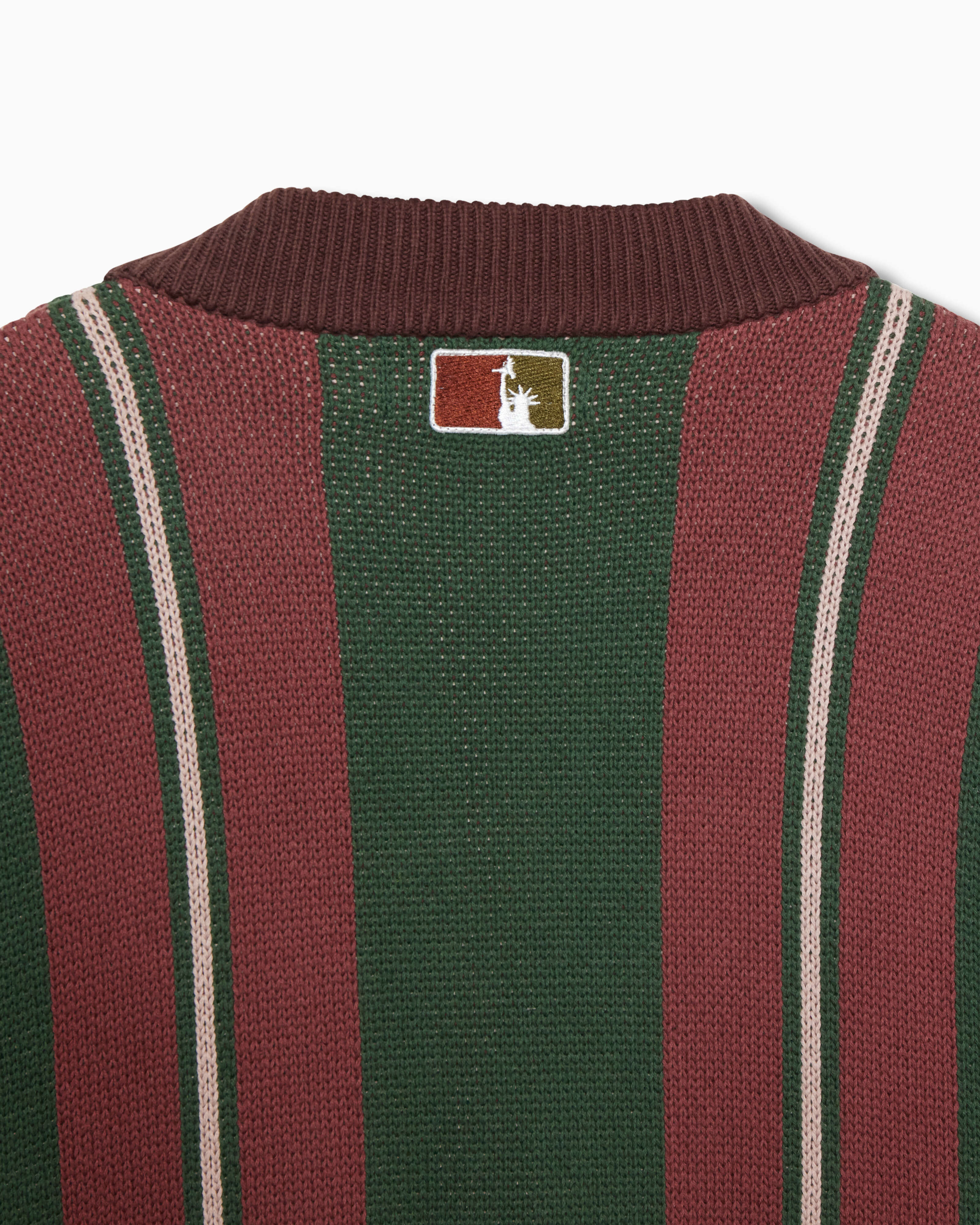 Closer look at the back of the sweater with an embroidered square patch below the nape of the neck and collar. The patch contains the upper half of the Statue of Liberty in a "NY Tough" inspired logo.