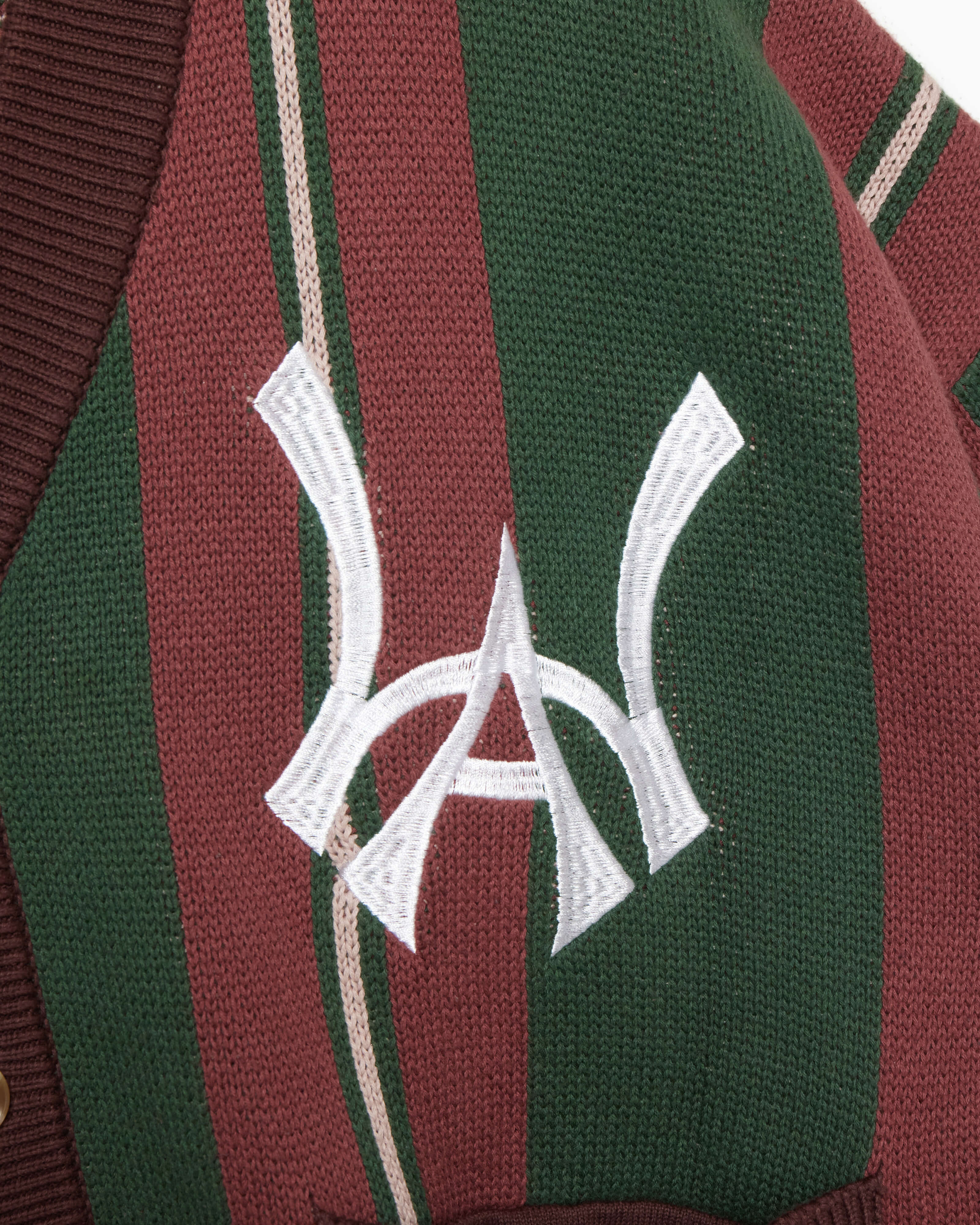 Closer look at the brand logo in a monogram font of connecting the "W" and "A" located on the upper left chest of the cardigan.