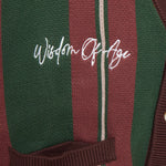 Closer Look at top right chest of the front of the cardigan with the brand name "Wisdom of Age" embroidered in a handwritten script cursive.