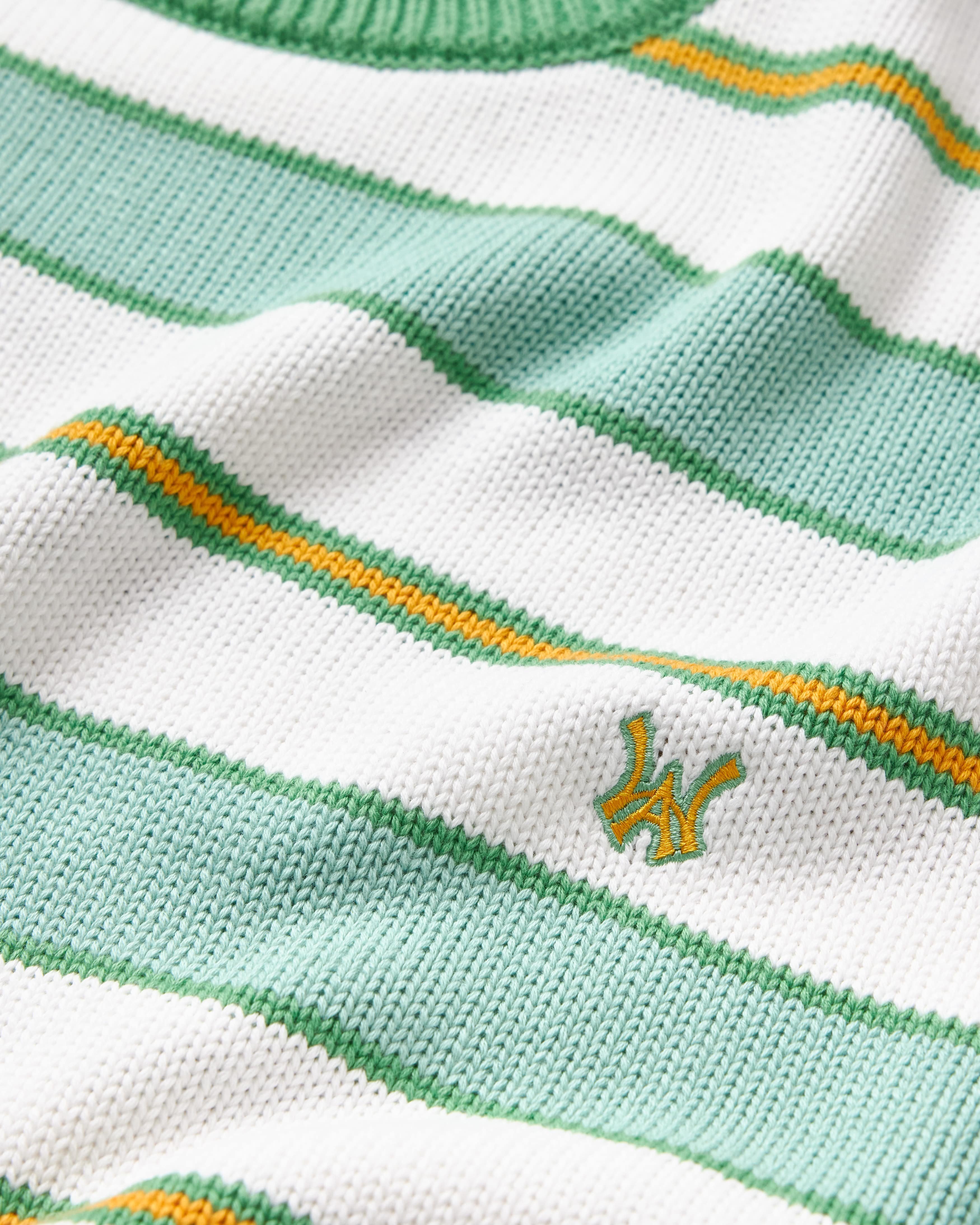 Close-up the WOA Knitted Shirt with green and white stripes and a logo.