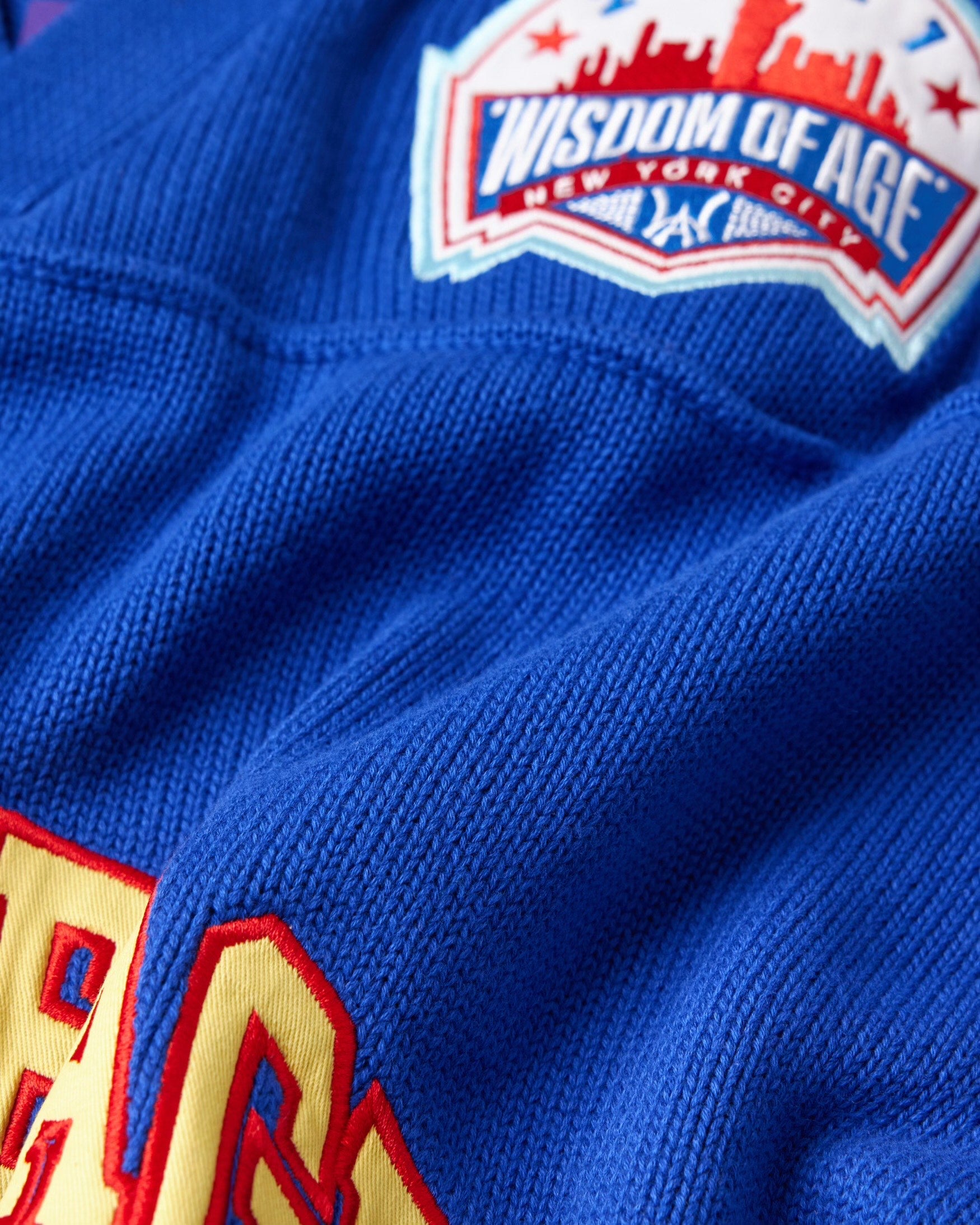 Close up of the front right WOA skyline  patch on the Wisdom Of Age Knit Football Jersey in Giant Blue