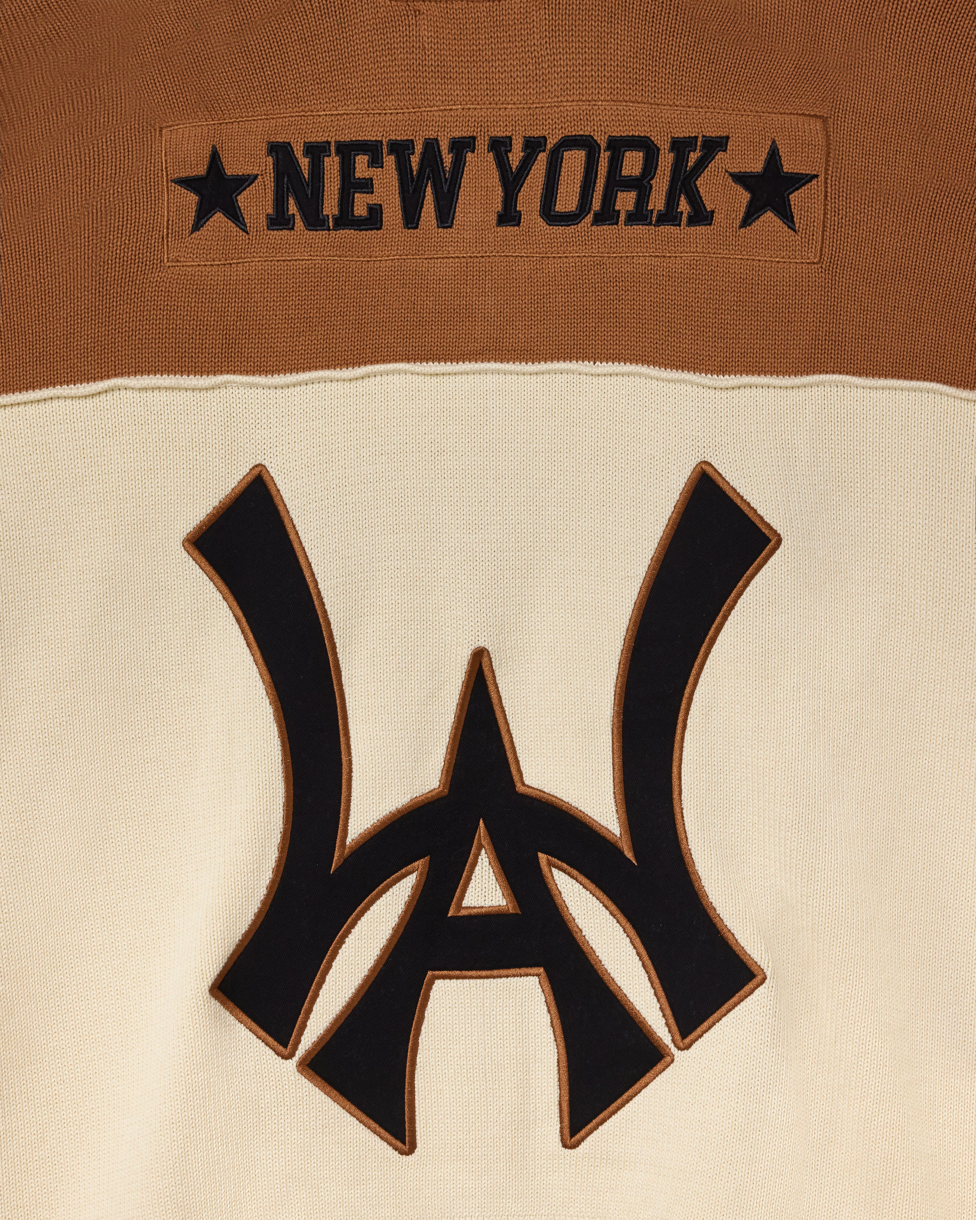 Close-up of the Wisdom Of Age Knit Football Jersey showing the WA logo with 'New York' on the nameplate  on a brown and beige background