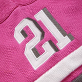 Close-up of the wisdom of age pink knitted football jersey with the number 21 on it.