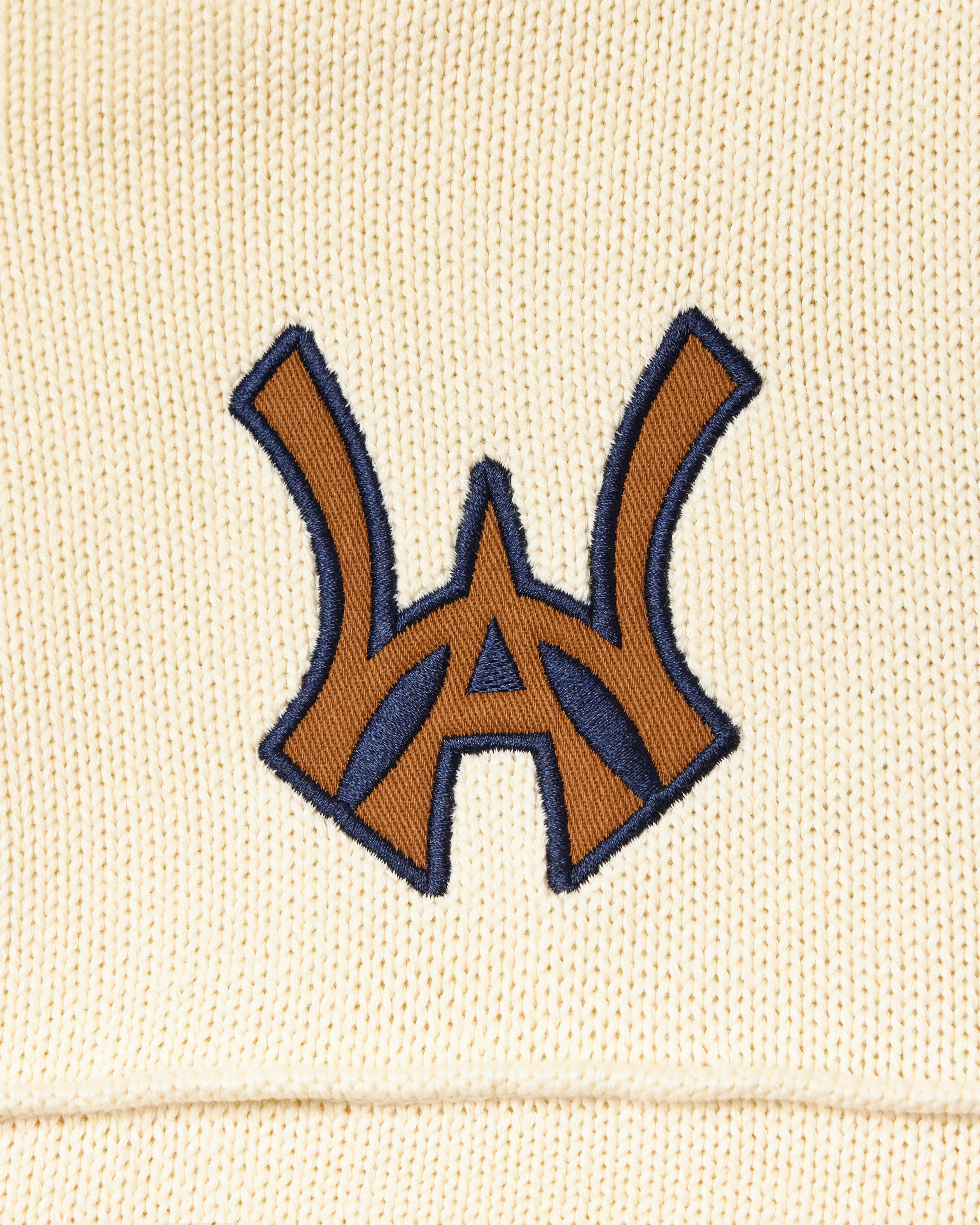 Embroidered WA logo on a cream fabric background