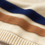 Close-up of a sweater with blue and brown stripes on cream fabric