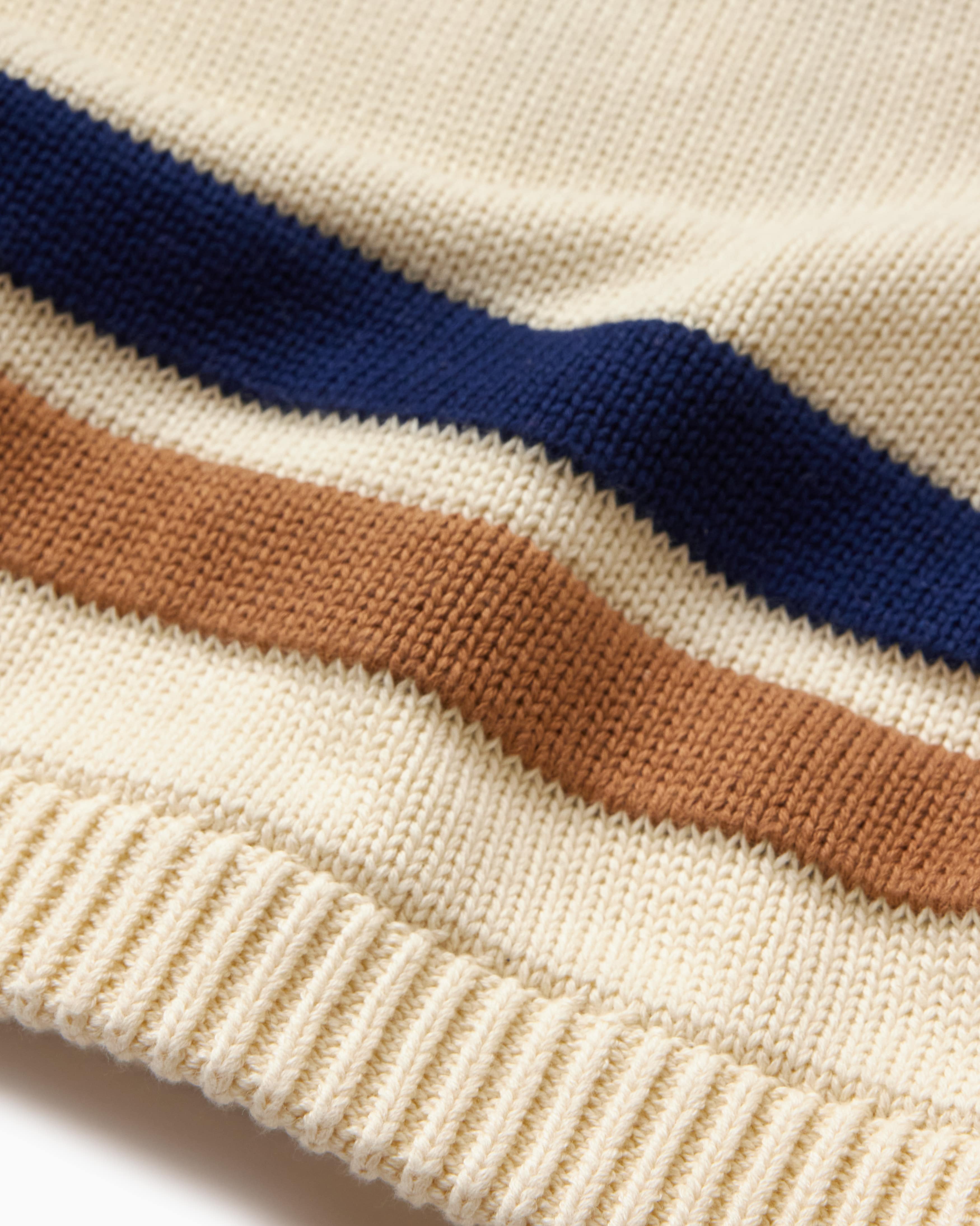 Close-up of a sweater with blue and brown stripes on cream fabric