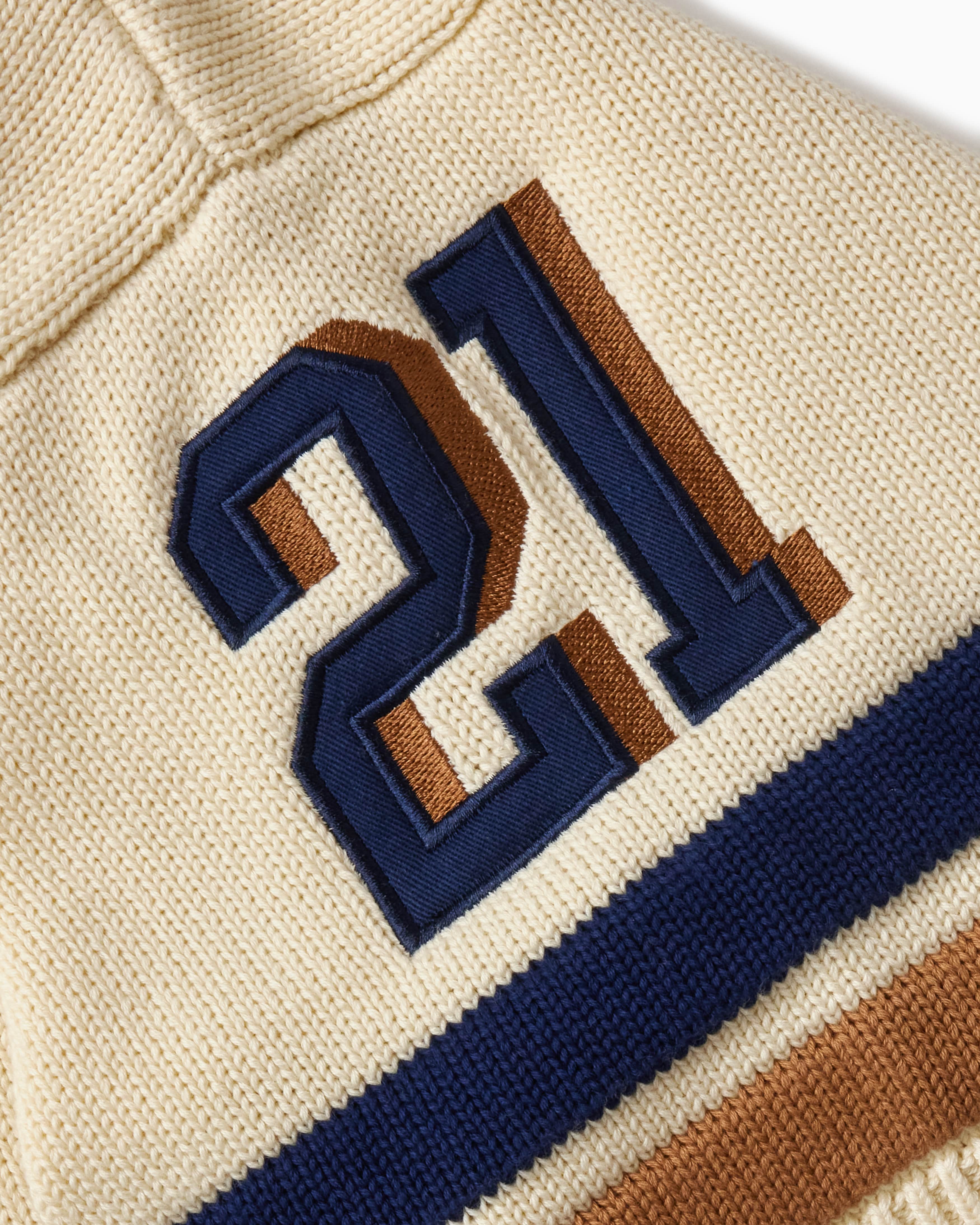 Close-up of the sleeve with blue and brown numbers '21' embroidered on it.