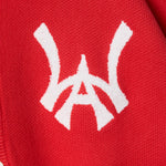 Closer look at the brand logo in a monogram font of connecting the "W" and "A" located on the upper left chest of the cardigan.