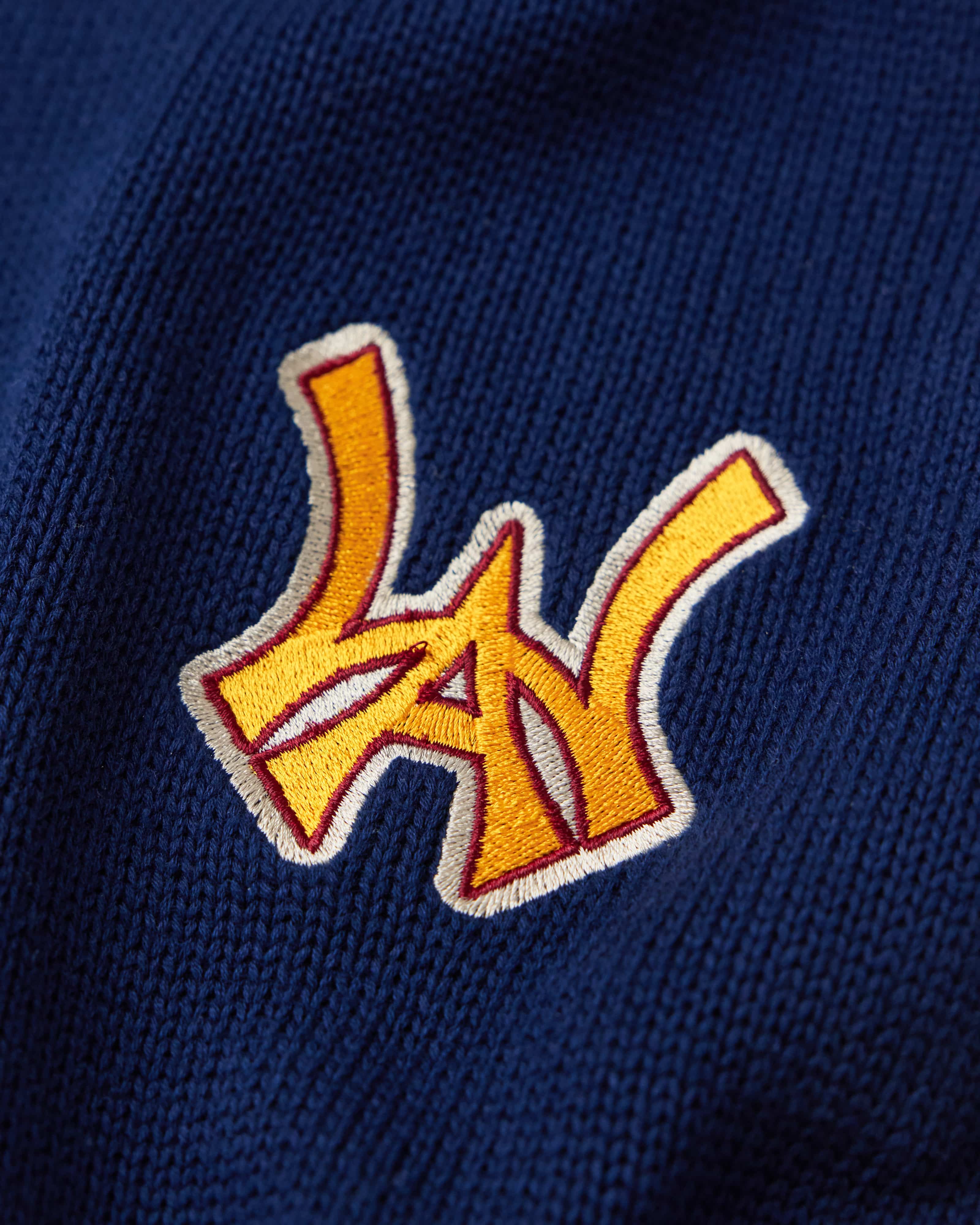 Close Up Of The Wisdom Of Age Knit Clinton Sweatpants Navy Front Logo Patch in Yellow.