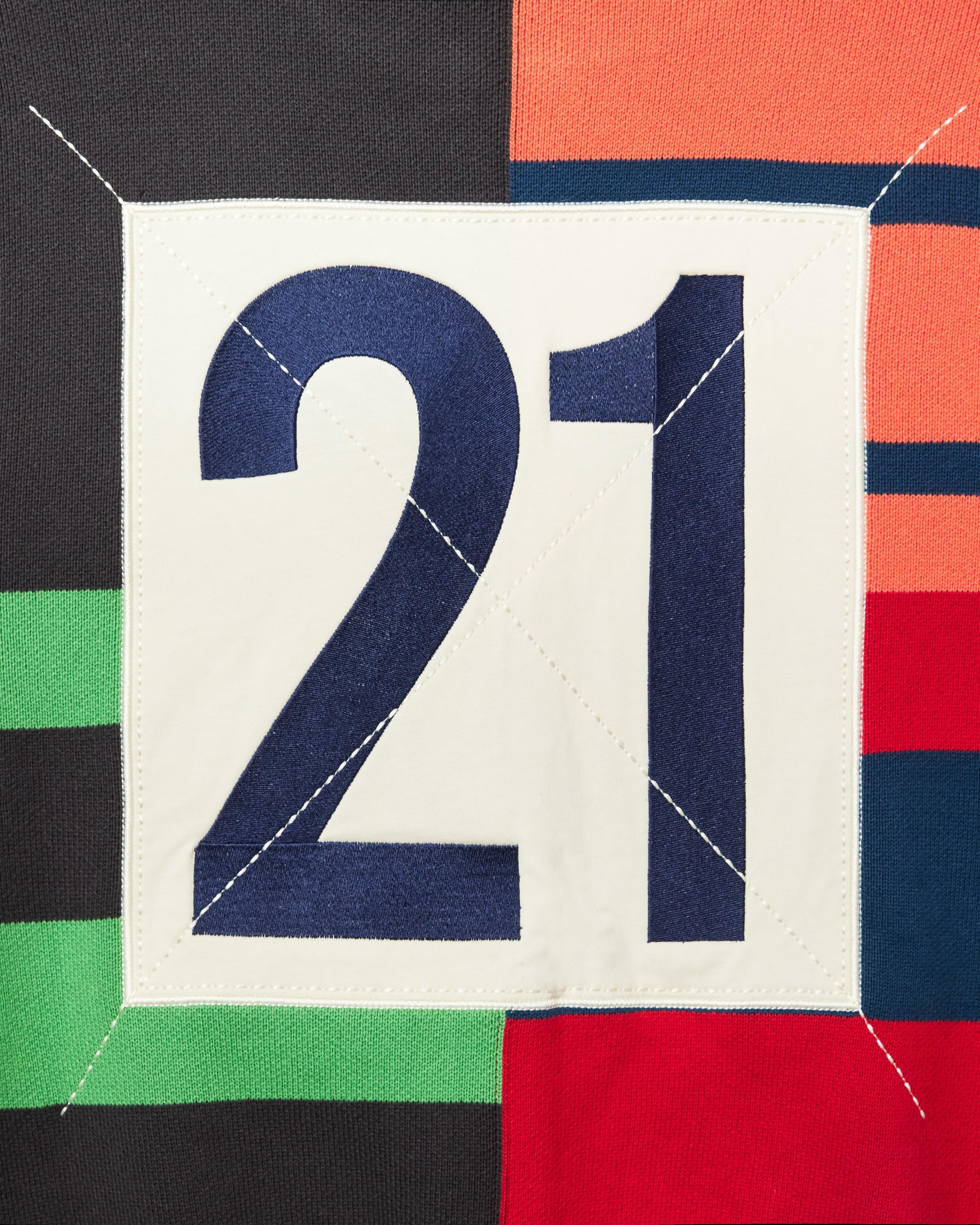 Close up of the rear of the Knit Zip up Hoodie. A navy number 21 within a cream square.