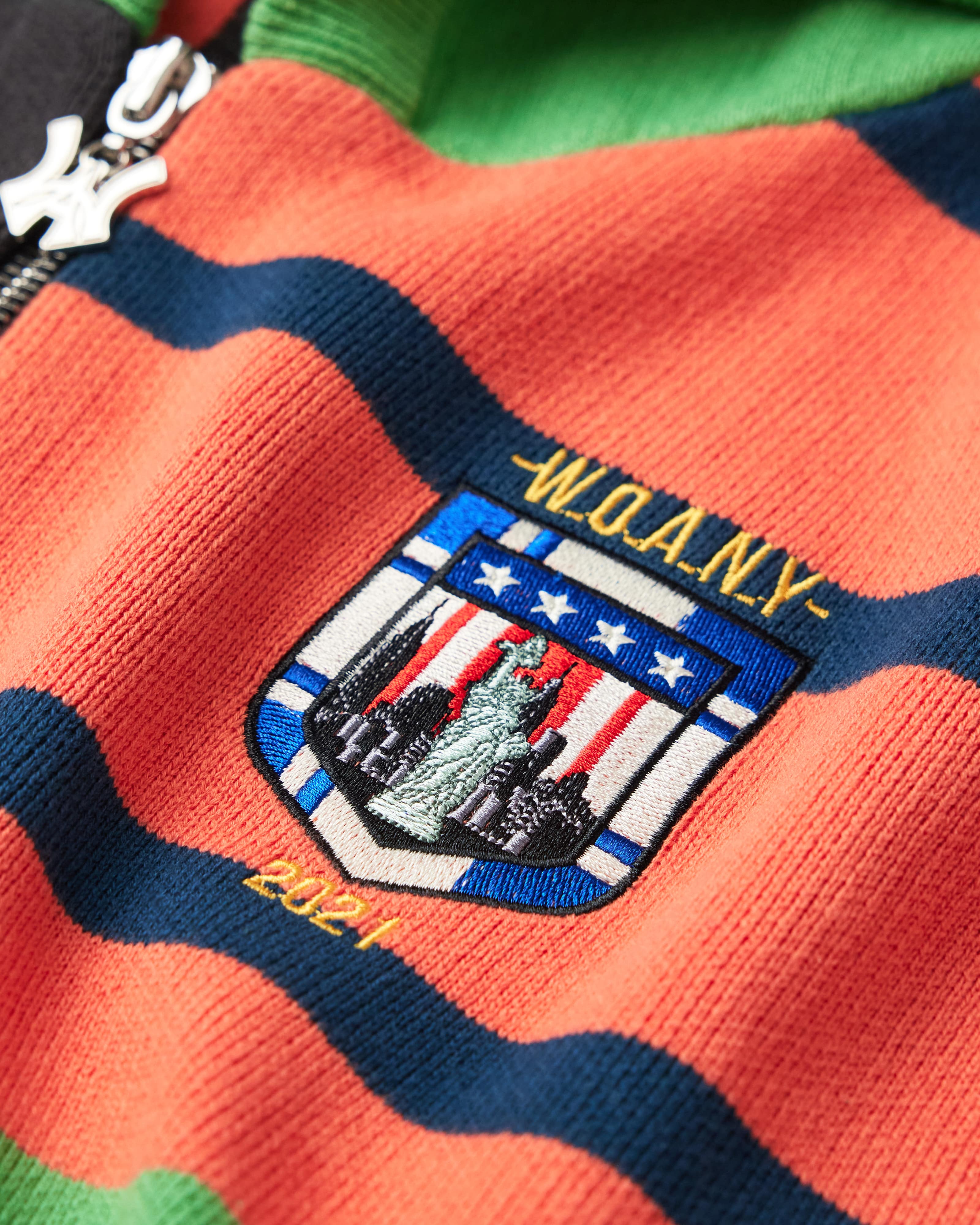 Close Up Of The Wisdom Of Age Knit Clinton Hoodie Multi-Color Front Patch.