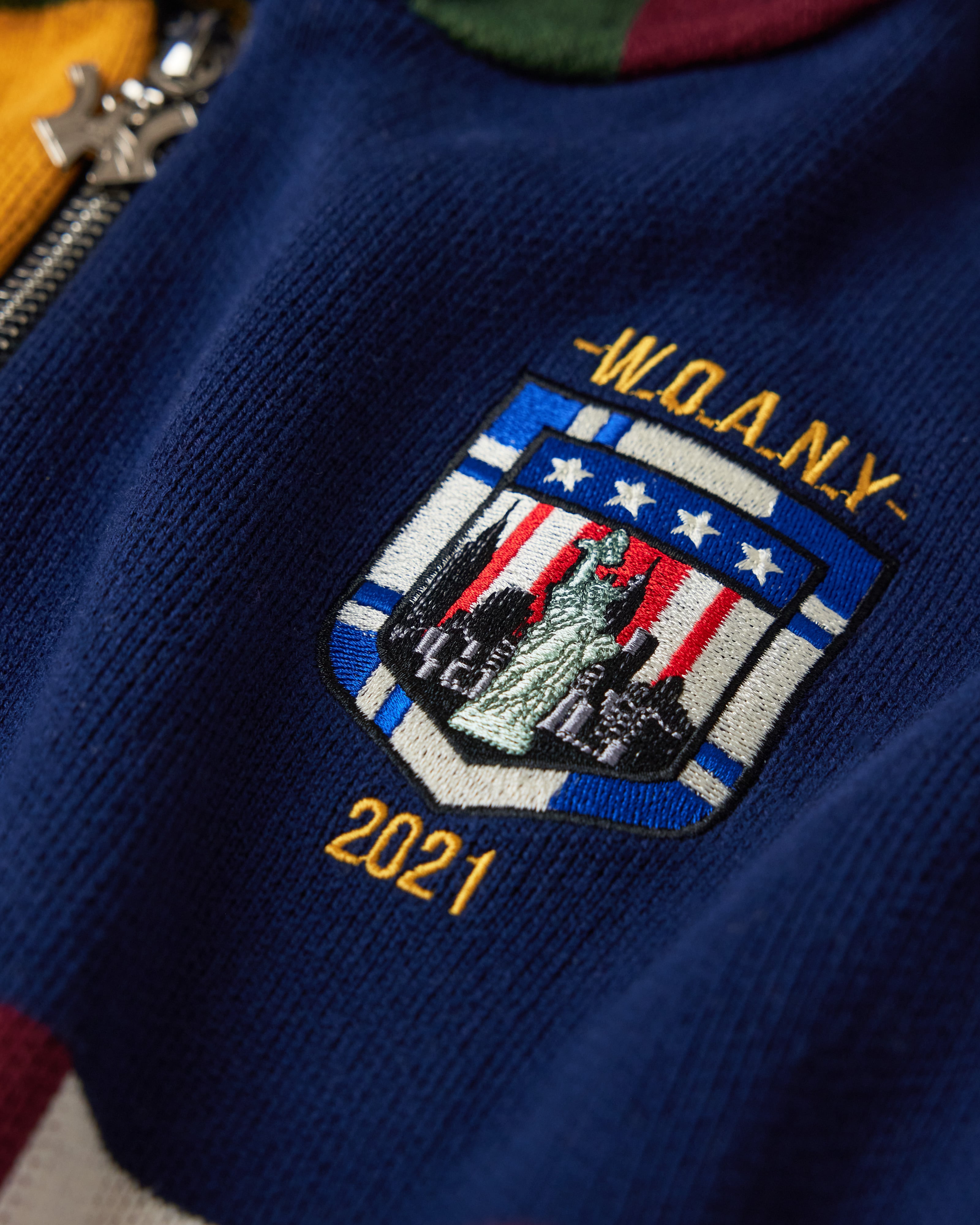 Close Up Of The Wisdom Of Age Knit Clinton Hoodie Multi-Color Front Patch.