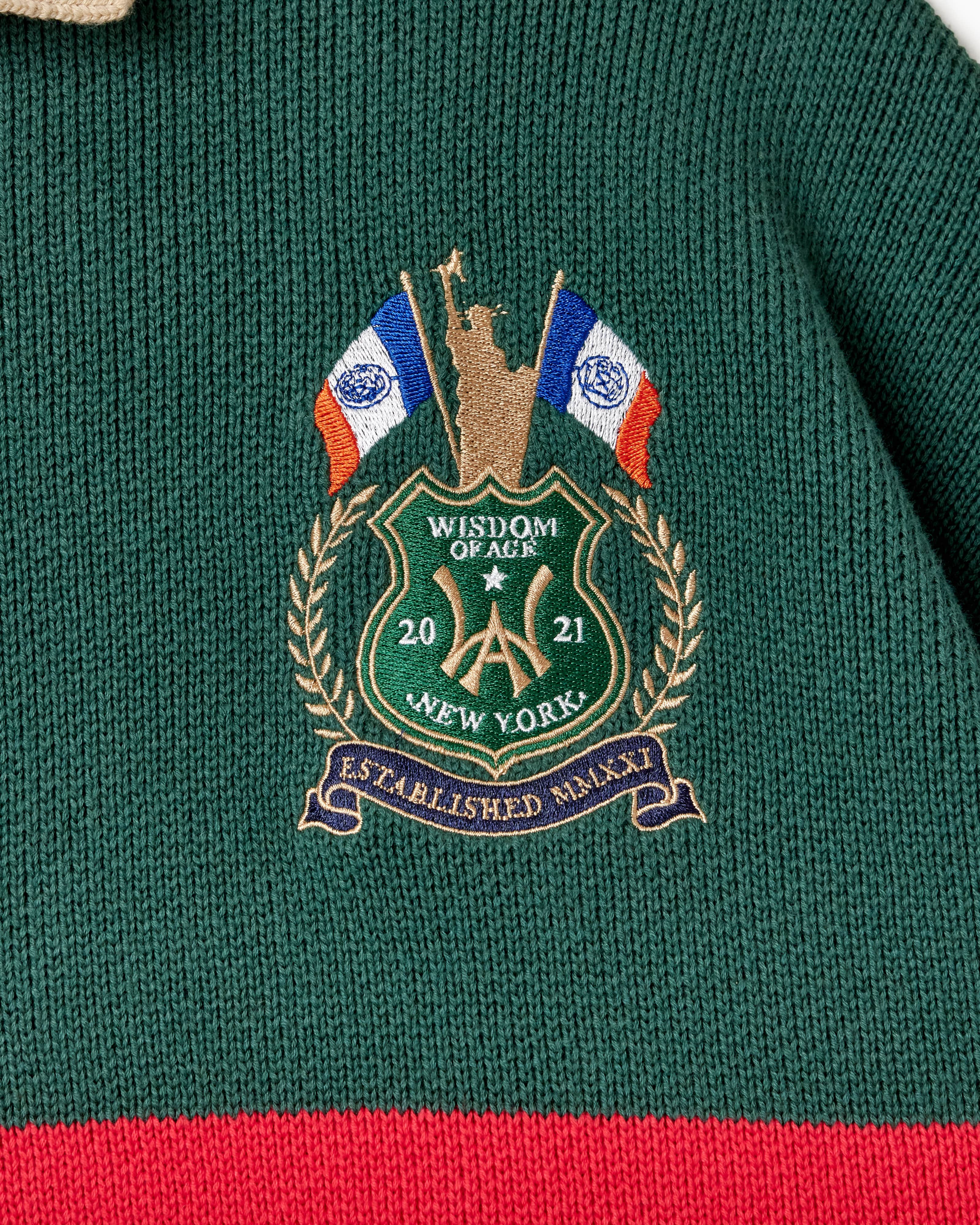 Embroidered WOA logo on a green and red garment with flags and text.