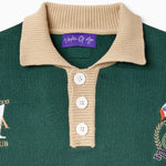 Green rugby sweater with beige collar and white buttons on a white background. Close up on the Wisdom Of Age label