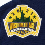 Close Up Of The Wisdom Of Age Knit Hockey Jersey Navy Front Patch.