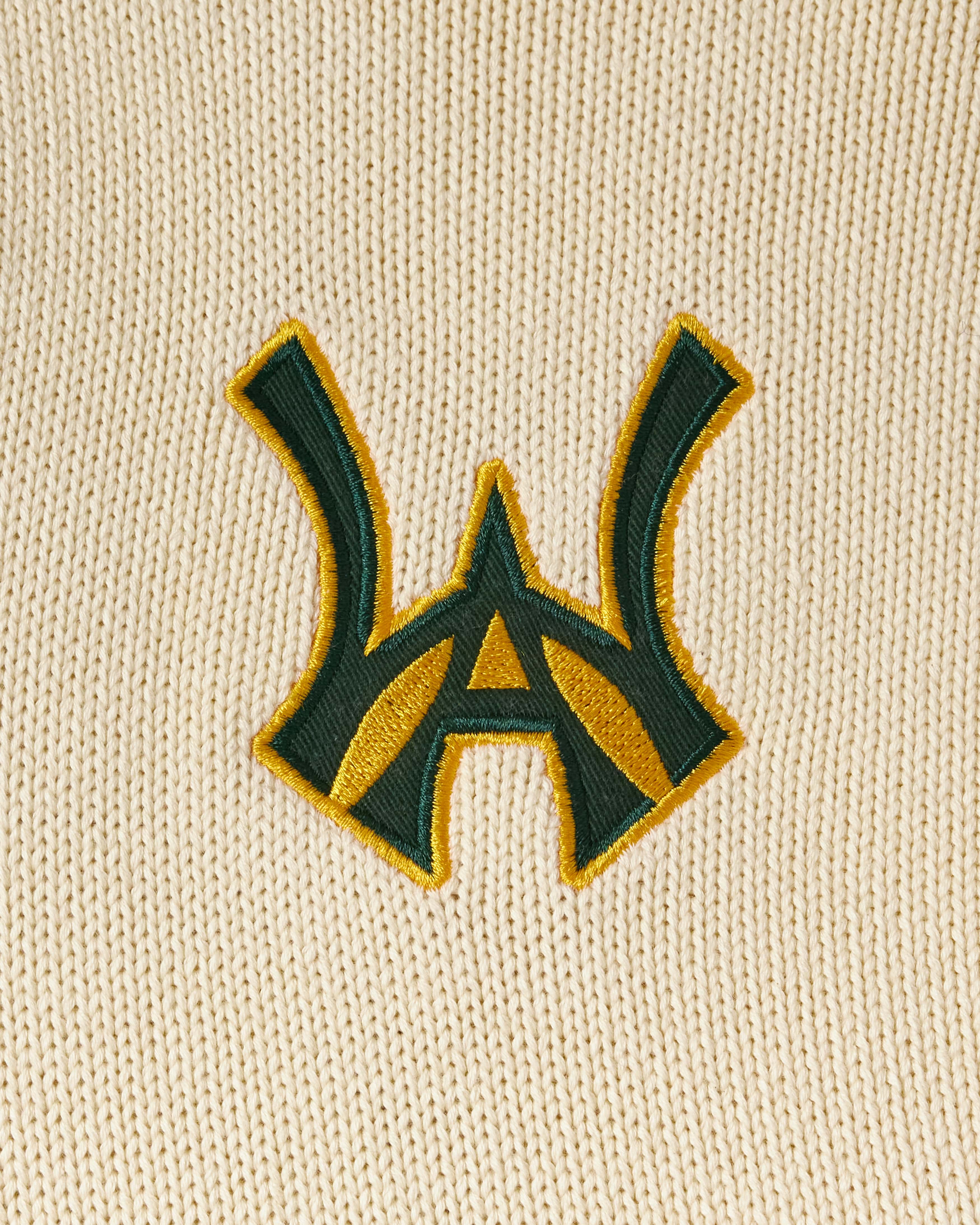 Embroidered WA logo on a Cream fabric background