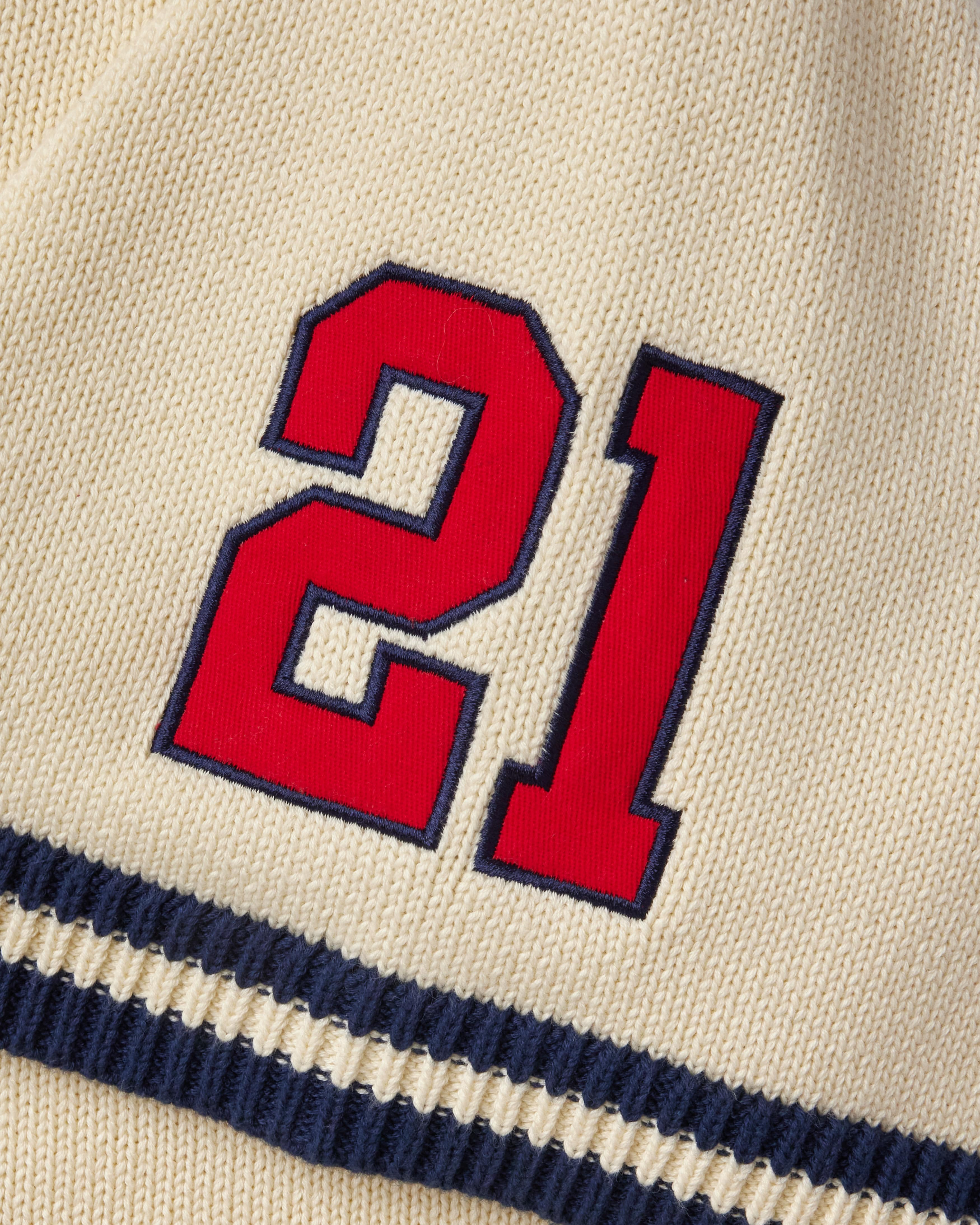 Red number 21 on a cream knitted baseball jersey with navy border