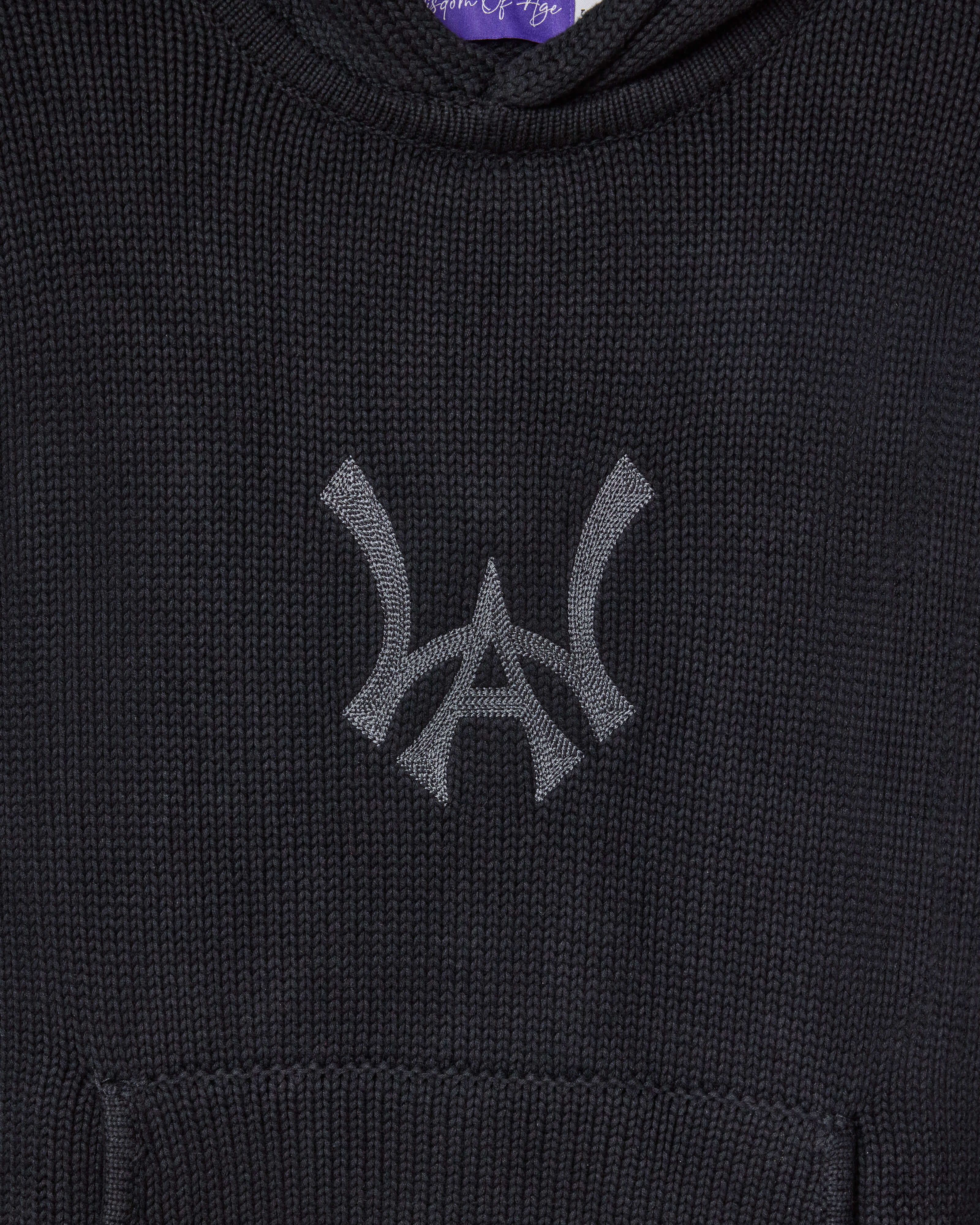 Closer look at the brand logo in a monogram font of connecting the "W" and "A" located on the front chest of the hoodie just above the kangaroo pocket.